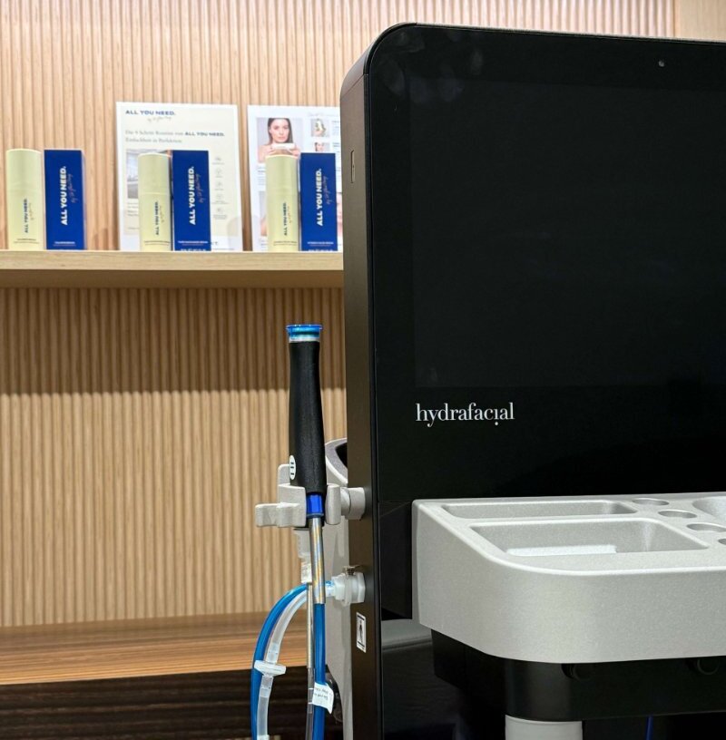Hydrafacial mit Kosmetik-Produkten im Hintergrund