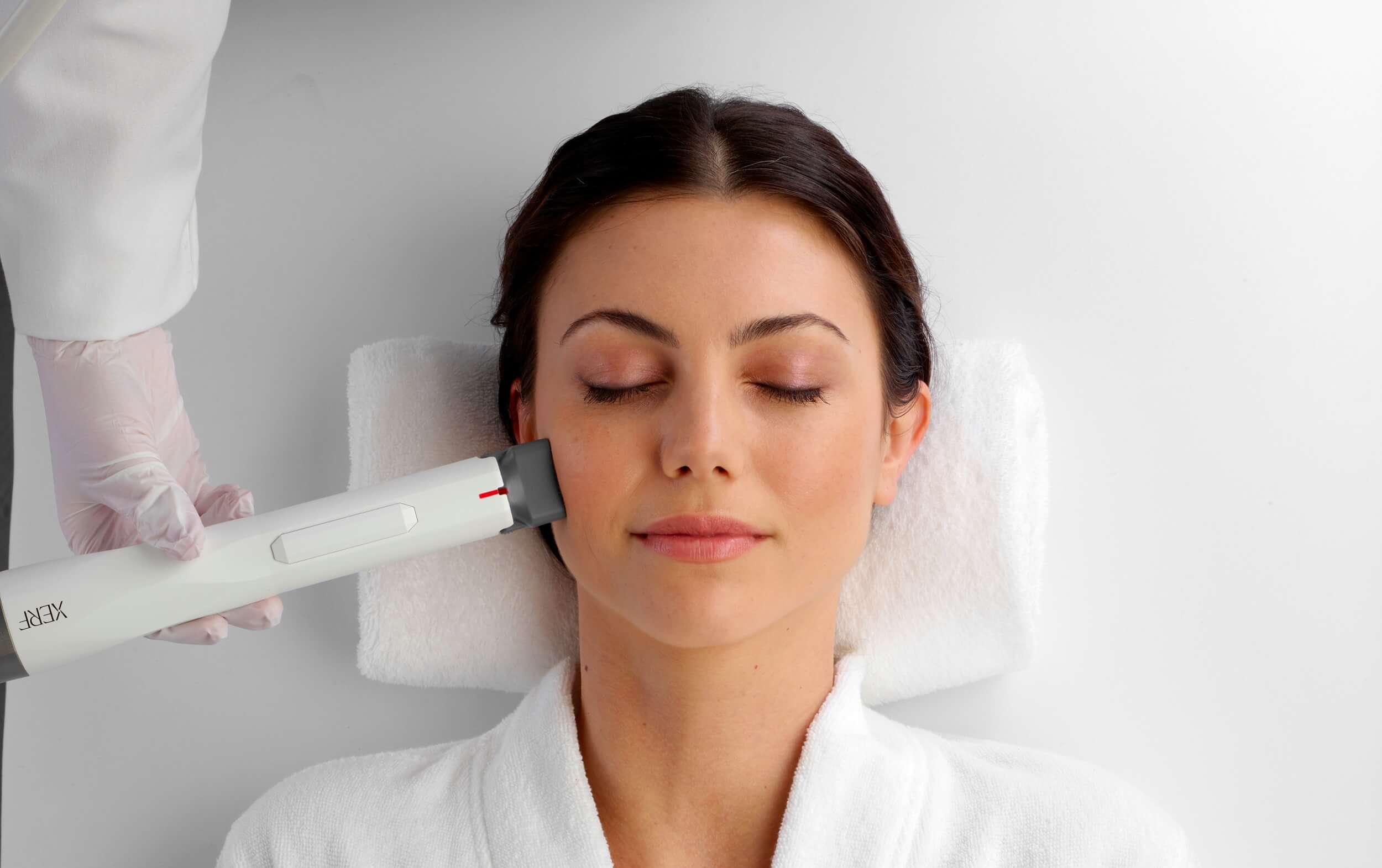 Eine Frau liegt entspannt während einer XERF-Behandlung in einer weißen Umgebung.